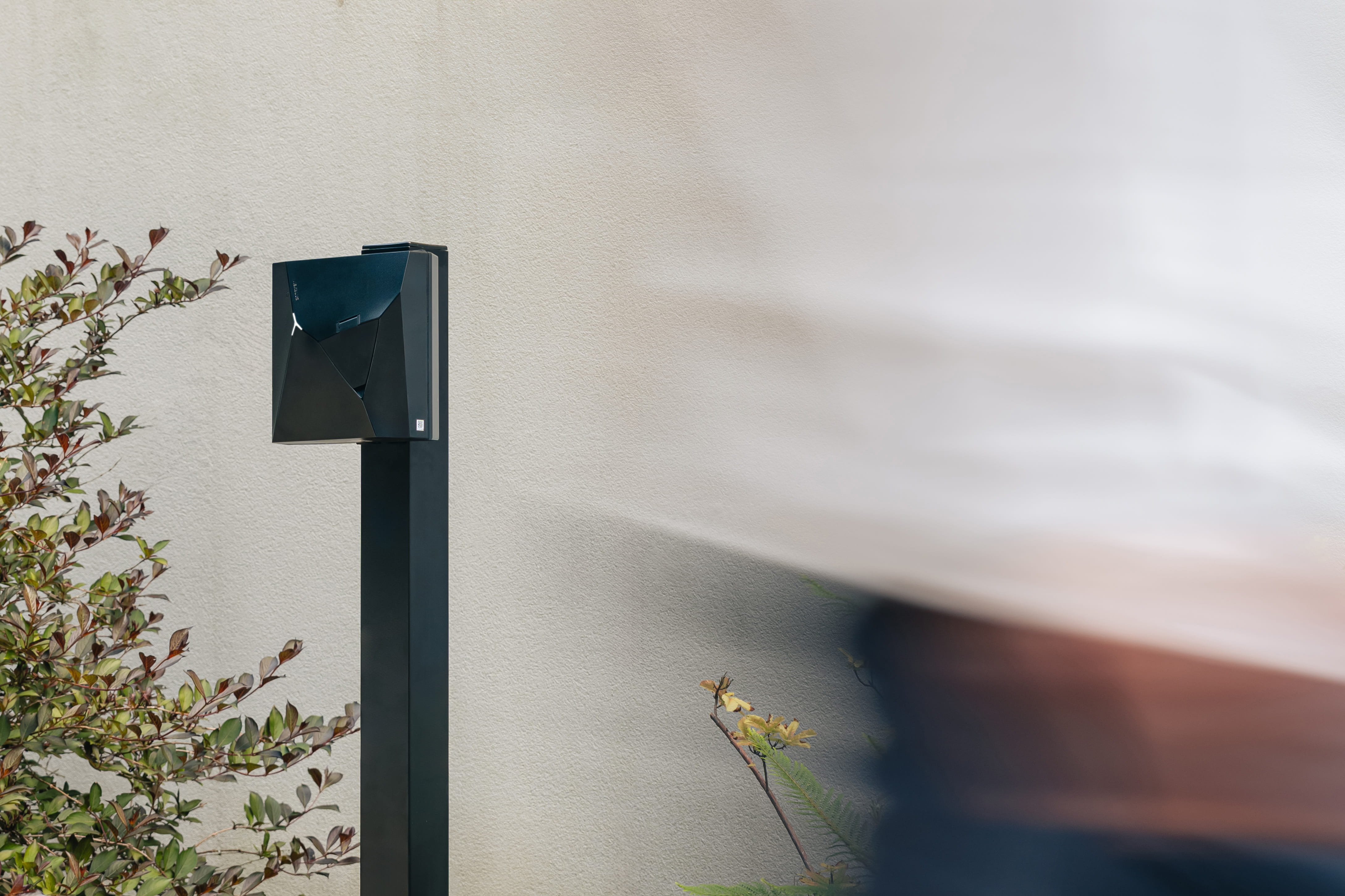 Zwart laadstation op een sokkel bij een woning