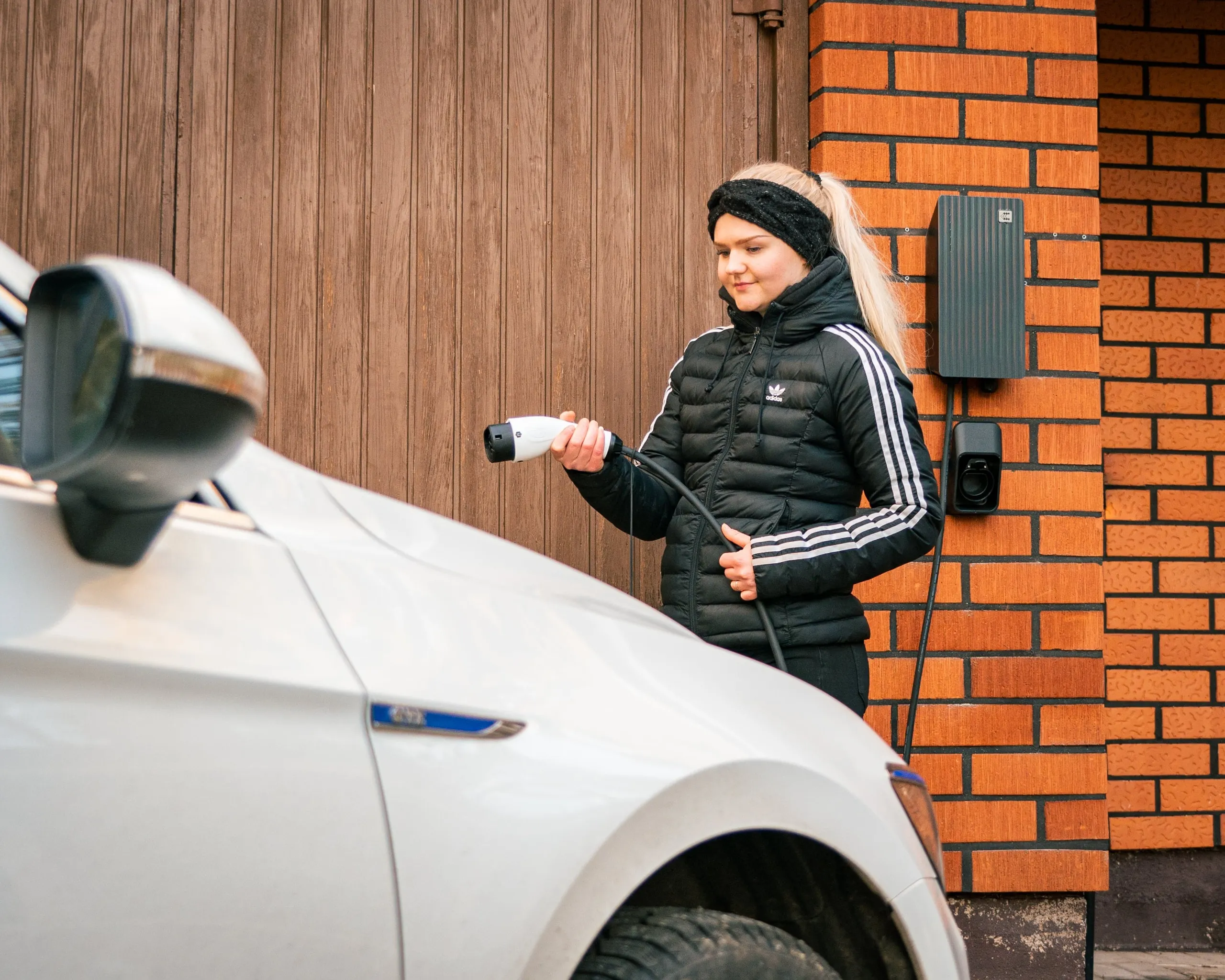Vrouw laadt haar elektrische auto bij haar woning op